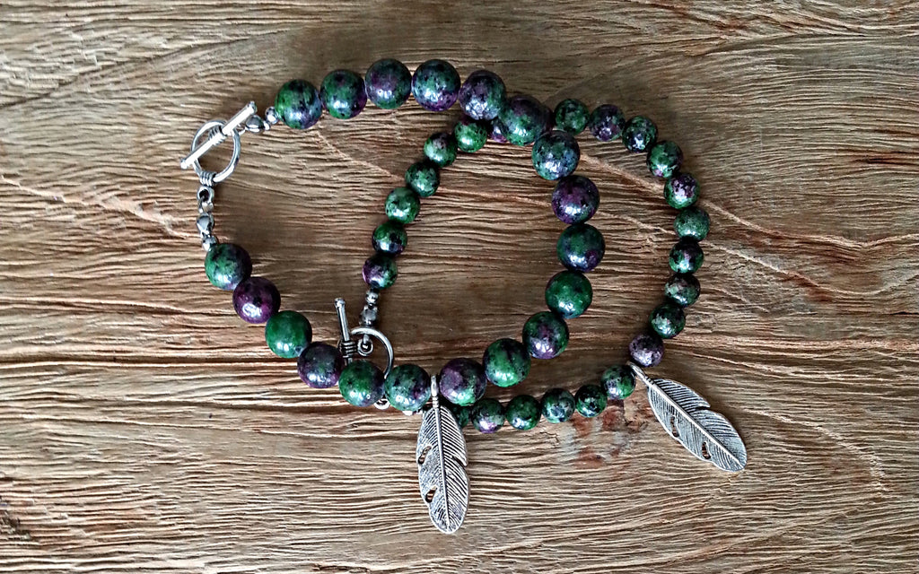 Comparison view of 8mm and 6mm ruby zoisite bead bracelets with silver feather charm